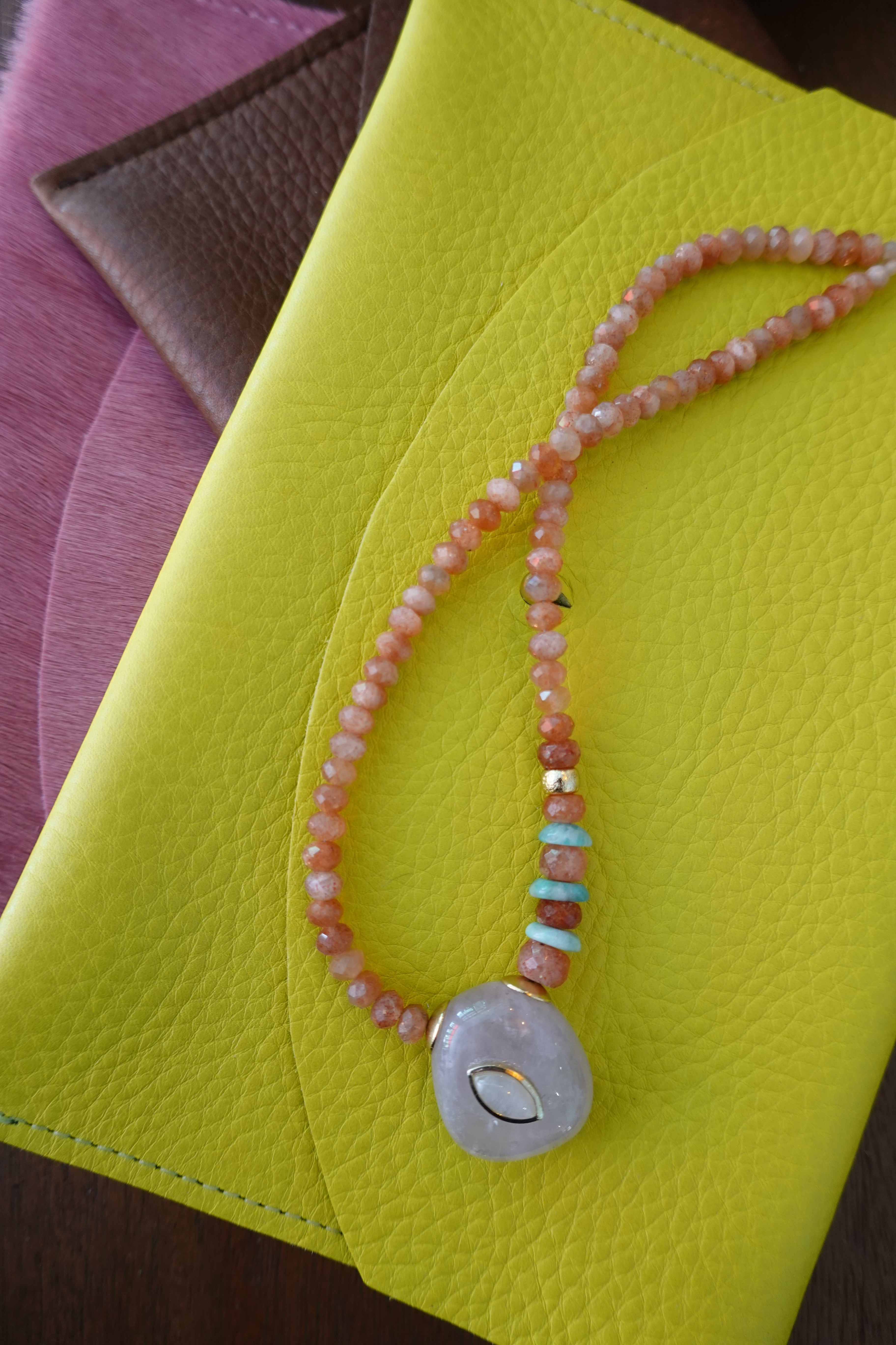 Necklace with colorful beads and a gold clasp on a yellow surface